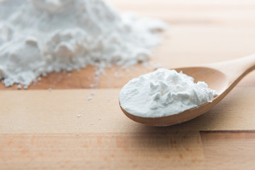 Close-up of tapioca starch or flour powder in wooden spoon with wooden background