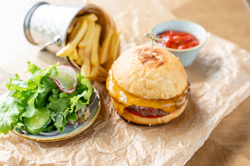 Unhealthy food. Cheeseburger with lettuce, tomato, fries, and melted cheese. The table in the restaurant.
