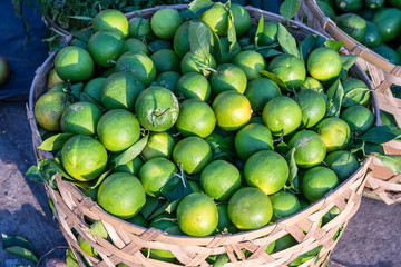 Fresh green oranges on the bamboo or wooden basket at farmer market in Ubud, island Bali, Indonesia