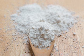 Close-up of tapioca starch or flour powder in wooden spoon with white background isolated