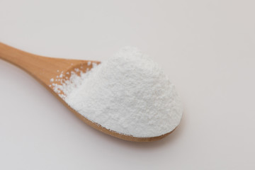 Close-up of tapioca starch or flour powder in wooden spoon with white background isolated