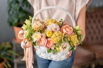 Flower arrangement in Wicker basket. Beautiful bouquet of mixed flowers in woman hand. Floral shop concept . Handsome fresh bouquet. Flowers delivery