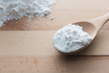 Close-up of tapioca starch or flour powder in wooden spoon on white background