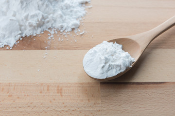 Close-up of tapioca starch or flour powder in wooden spoon on white background