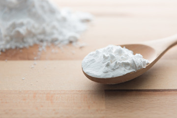 Close-up of tapioca starch or flour powder in wooden spoon on white background