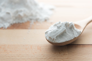 Close-up of tapioca starch or flour powder in wooden spoon on white background