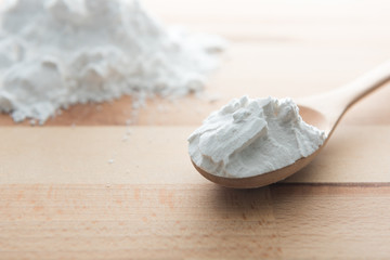 Close-up of tapioca starch or flour powder in wooden spoon on white background