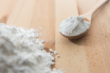 Close-up of tapioca starch or flour powder in wooden spoon on white background