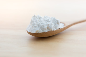 Close-up of tapioca starch or flour powder in wooden spoon on white background