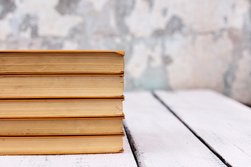 Stack of old ancient shabby books on a white wooden background.
