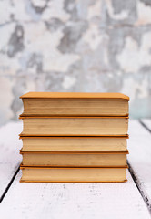 Stack of old ancient shabby books on a white wooden background.