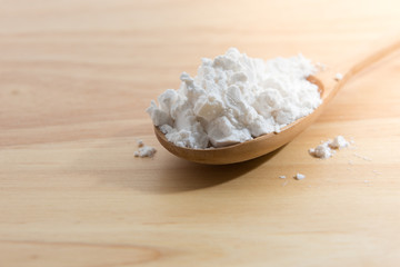 Close-up of tapioca starch or flour powder in wooden spoon with wooden background