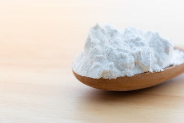 Close-up of tapioca starch or flour powder in wooden spoon with wooden background