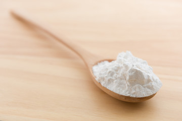Close-up of tapioca starch or flour powder in wooden spoon with wooden background