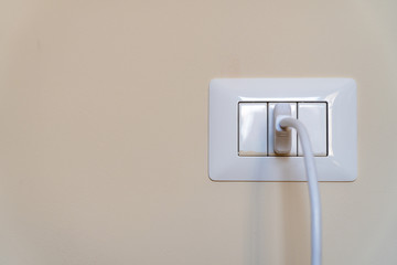 white cable plugged in a italian white electric outlet mounted on wall