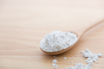 Close-up of tapioca starch or flour powder in wooden spoon with wooden background