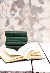 Stack of old ancient shabby books on a white wooden background.