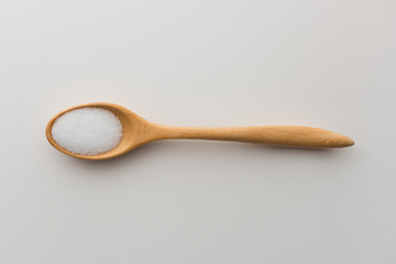 Top view of salt crystals powder on wooden spoon white background isolate with clipping path