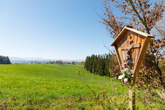 Wayside cross in bavaria with flowers in spring
