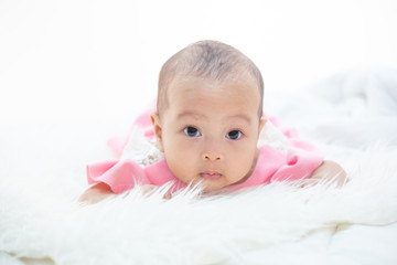 The baby is lying on a white bed.