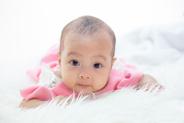 The baby is lying on a white bed.
