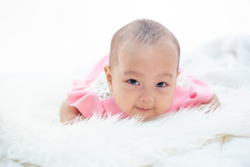 The baby is lying on a white bed.