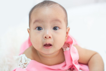The baby is lying on a white bed.