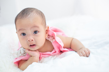 The baby is lying on a white bed.