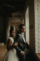 Bride and groom stand near the window. Interracial marriage. Asian bride and groom.