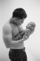 The baby sleeps in the hands of a strong father.