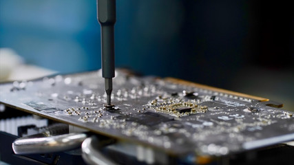 PC technician screws chipset of graphics card to ventilator installing it.