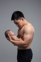 The baby sleeps in the hands of a strong father.