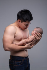 The baby sleeps in the hands of a strong father.