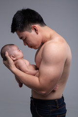 The baby sleeps in the hands of a strong father.