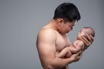 The baby sleeps in the hands of a strong father.