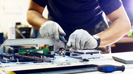 Professional technician detaches monoblock hard drive repairing it in workshop.