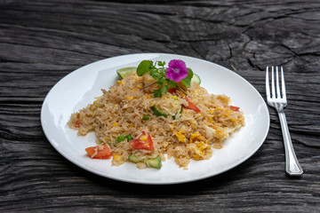 Fried rice with shrimps and vegetables in a white dish on an old wooden table, close up . Thai food...
