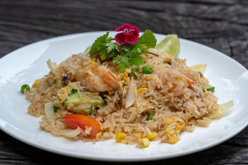 Fried rice with shrimps and vegetables in a white dish on an old wooden table, close up . Thai food...