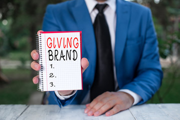 Text sign showing Giving Brand. Business photo text The process of giving a Name to a company products or services Man holds empty paper with copy space in front of him
