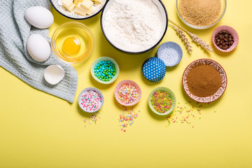 Baking ingredients for cupcakes or muffins on yellow copy space background