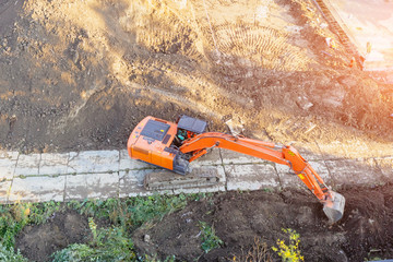 Excavator on caterpillars in the foundation pit during the construction of the building foundation, digging. Aerial top view.