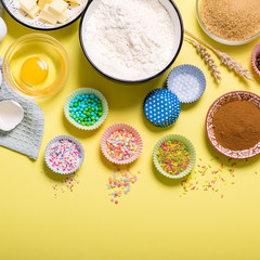 Baking ingredients for cupcakes or muffins on yellow copy space background