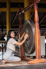 Obraz na płótnie Canvas Asian woman touching big gong