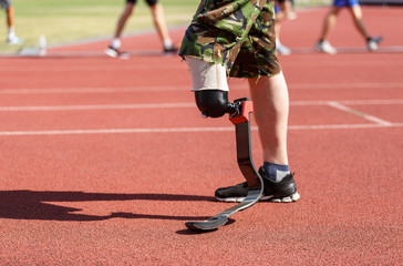 Ukrainian amputee veteran running with a prostethic leg. Paraolympic athlete with amputated limb training outdoors.