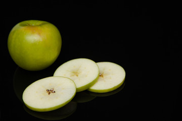 green apple slices on a black background with reflection