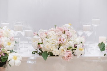 Beautiful artistic wedding design in soft colors with fresh flowers and white candles