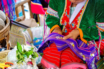 Closeup hands of Thailander Hill tribe ladies are demonstrating the sewing and decorating of costumes for tourists in her village.