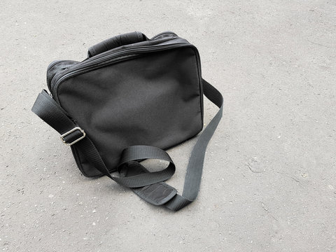 Black business satchel bag left behind on the concrete floor, man fashion accessories for carrying an laptop or documents during business trip in urban area concept