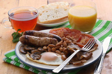 Classic English breakfast served: eggs, bacon, beans, juice and tea