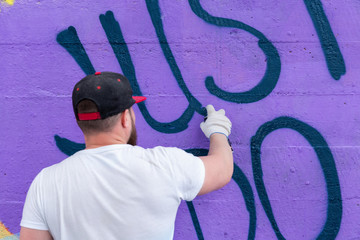 Graffiti artist painting with aerosol spray bottle